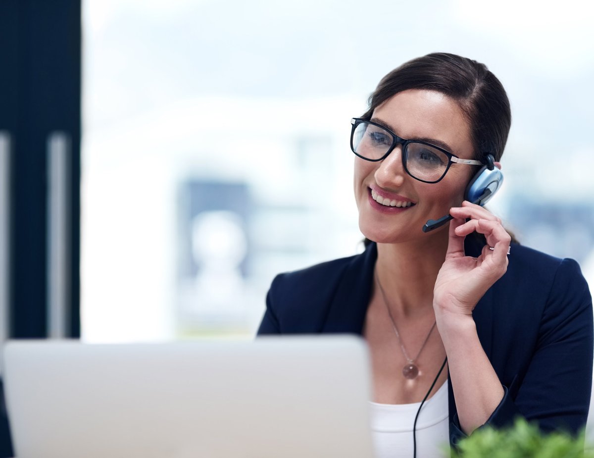 Shot of a happy businesswoman talking on her headset while working on her laptop in the office